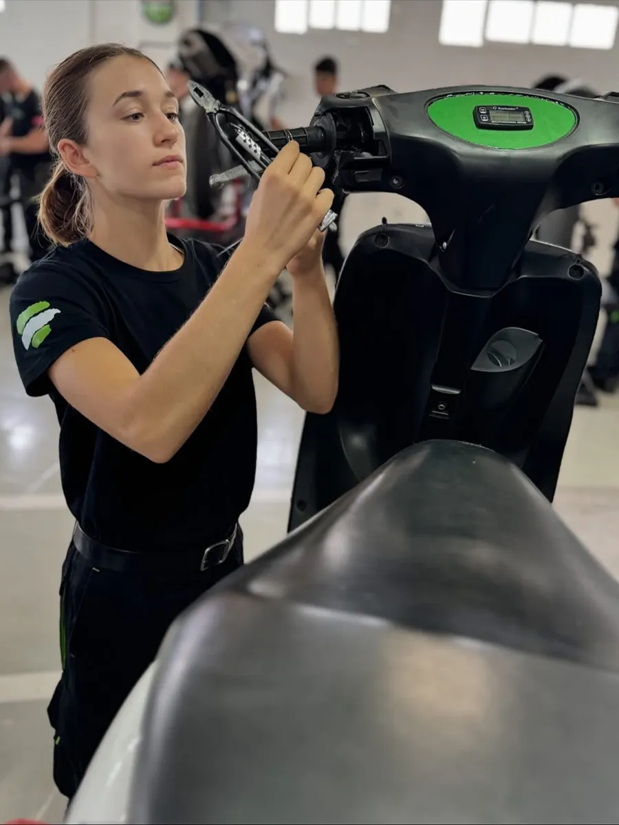 Alumna de EMA Competición ajustando el manillar de un scooter en el taller