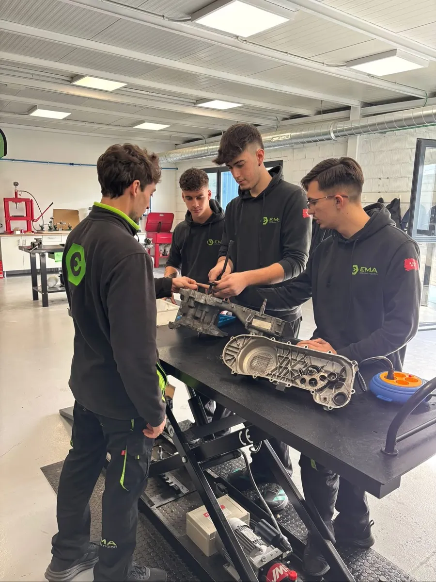 Profesor de EMA Competición explicando un cárter de motor a tres alumnos